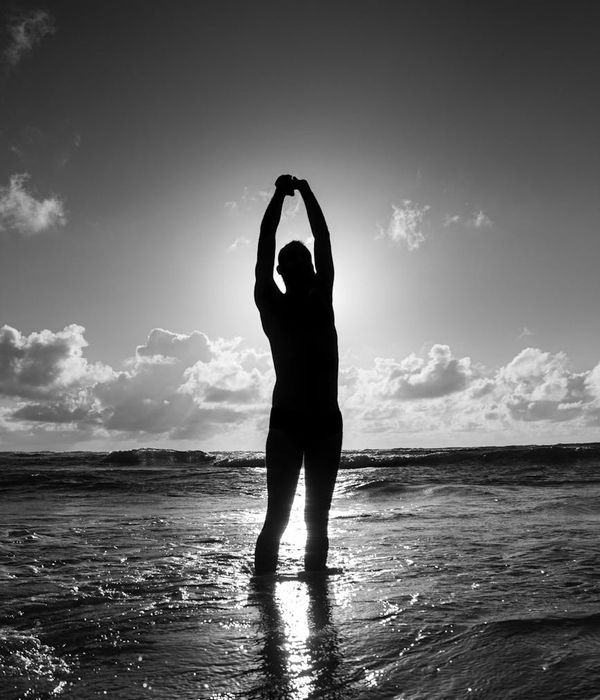 Silhouette of a person stretching during sunrise, conveying energy and vitality.
